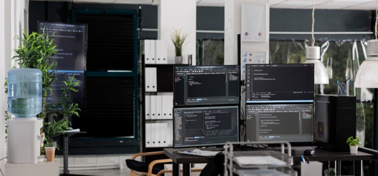 Stanowisko pracy z kilkoma monitorami wyświetlającymi kod w nowoczesnym biurze – profilowanie rodo