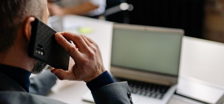 Mężczyzna rozmawia przez telefon przy laptopie – kara za niezapewnienie niezależności IOD